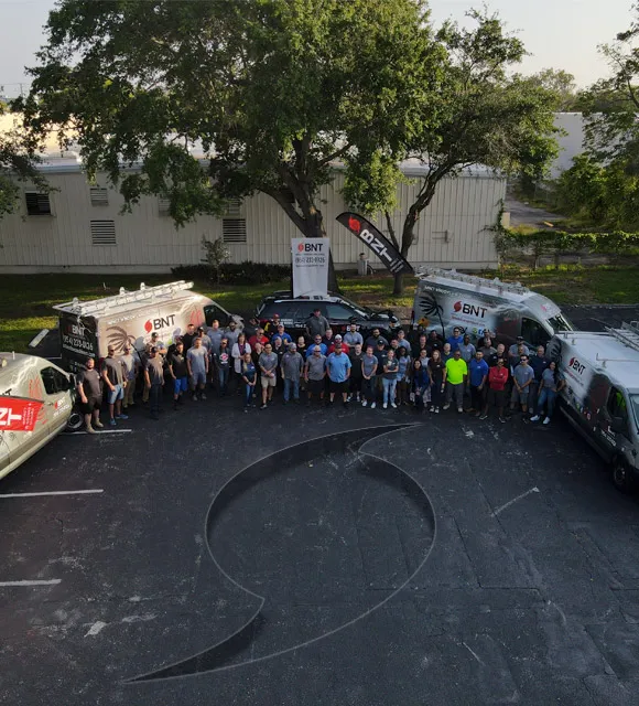 BNT Impact Windows and Doors crew standing outside with branded vans in Florida